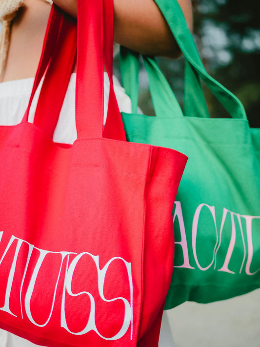 a woman carrying two red and green shopping bags