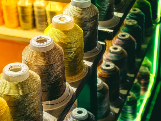 a row of spools of thread sitting on top of a shelf