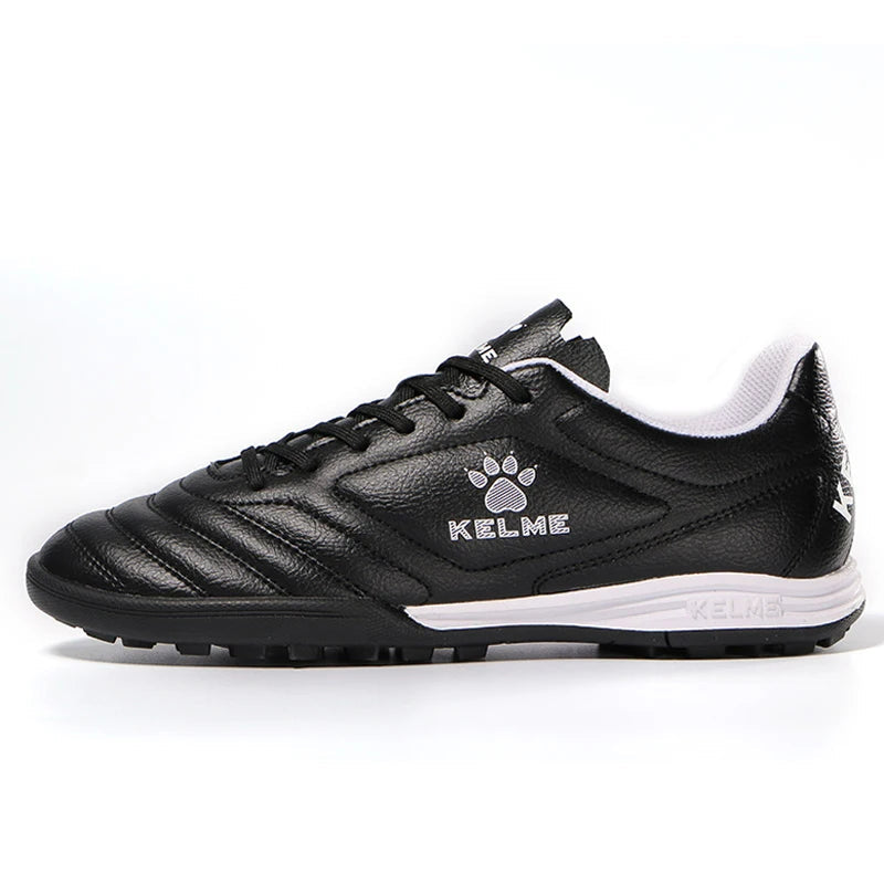 Black soccer shoe with white sole on a white background, featuring Kelme logo.